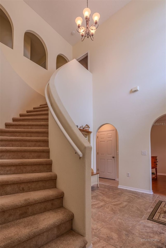 staircase with a high ceiling and a notable chandelier