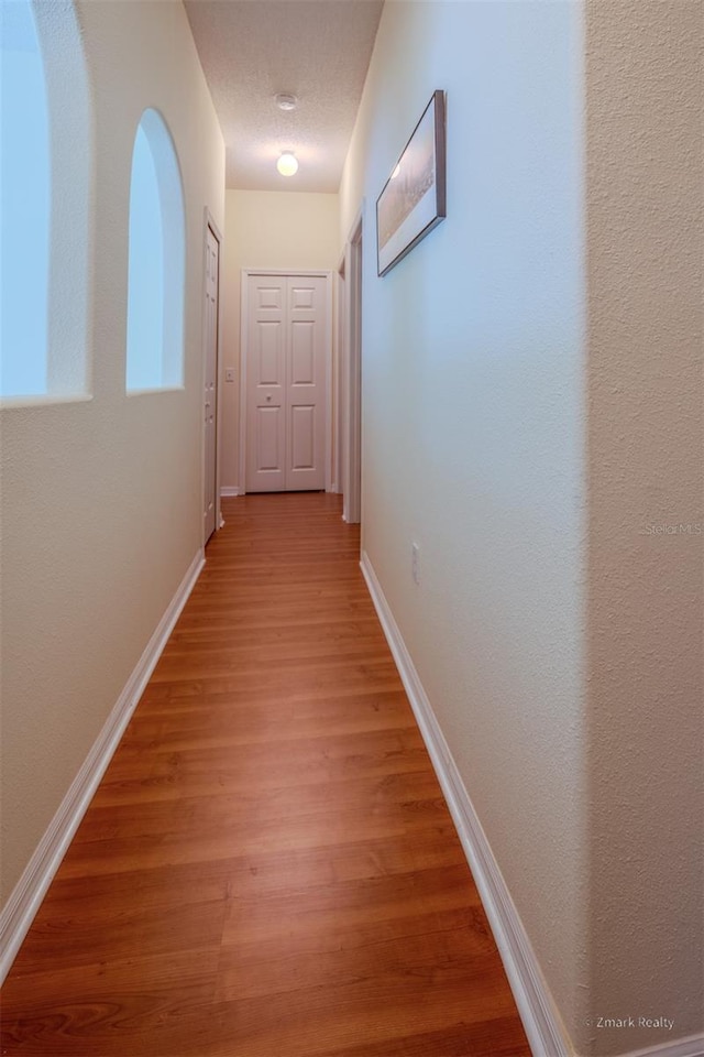 hallway featuring hardwood / wood-style flooring and a textured ceiling