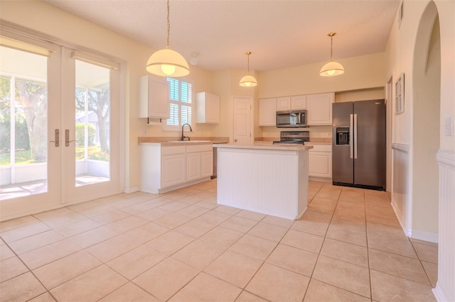 kitchen with pendant lighting, white cabinets, sink, a kitchen island, and stainless steel appliances