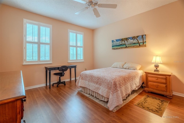 bedroom featuring ceiling fan, wood-type flooring, and a textured ceiling