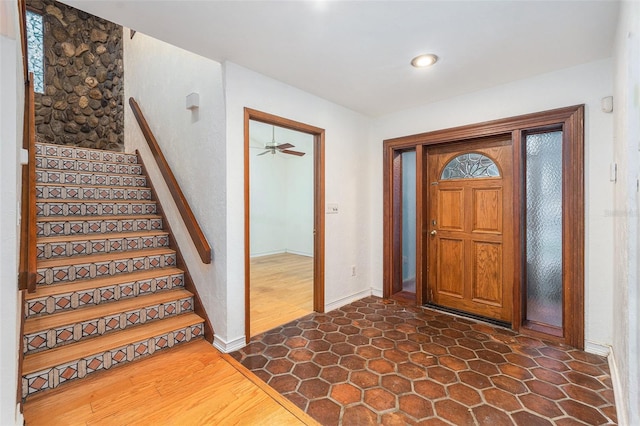 foyer entrance with ceiling fan and dark wood-type flooring