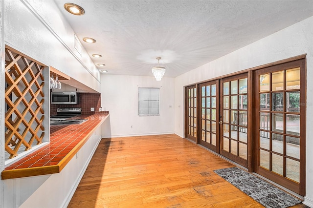 kitchen with decorative light fixtures, stainless steel appliances, plenty of natural light, and tile counters