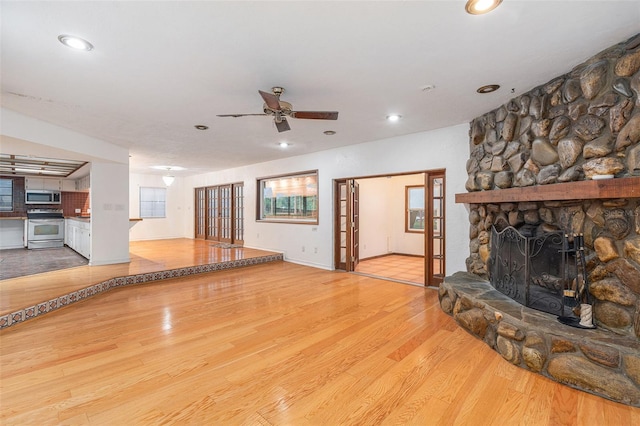 unfurnished living room featuring ceiling fan, a fireplace, and light wood-type flooring