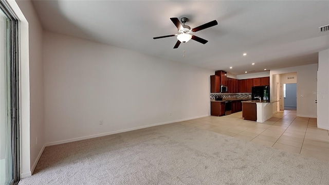 unfurnished living room with ceiling fan, light colored carpet, and sink