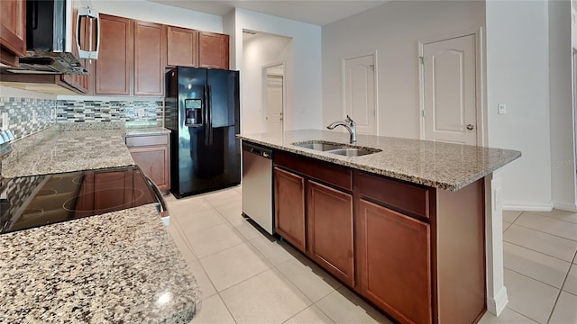 kitchen with an island with sink, appliances with stainless steel finishes, light stone countertops, and sink