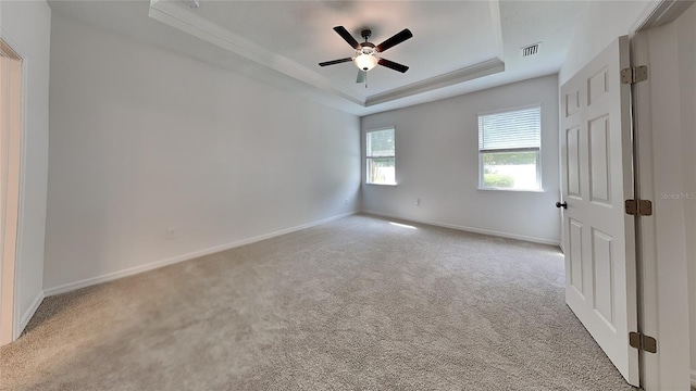 carpeted empty room featuring a raised ceiling, crown molding, and ceiling fan