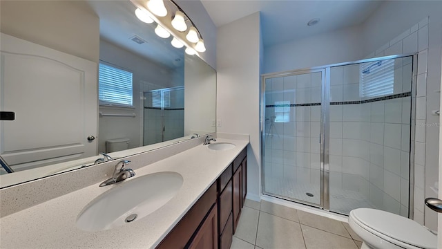 bathroom featuring tile patterned flooring, vanity, toilet, and a shower with door