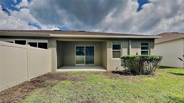 back of property featuring a lawn and a patio