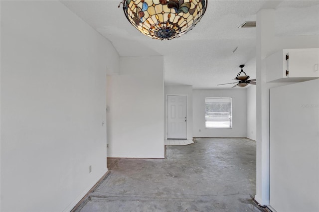 unfurnished living room with ceiling fan and a textured ceiling