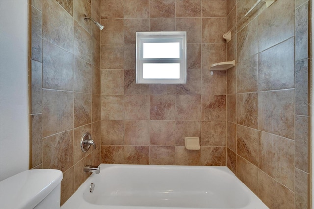 bathroom featuring tiled shower / bath combo and toilet