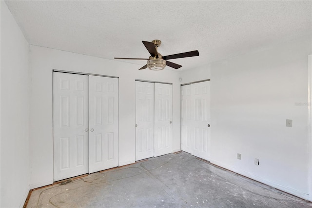 unfurnished bedroom featuring two closets, a textured ceiling, and ceiling fan