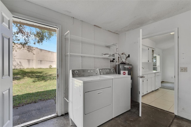 laundry area featuring a textured ceiling, washer and clothes dryer, and water heater