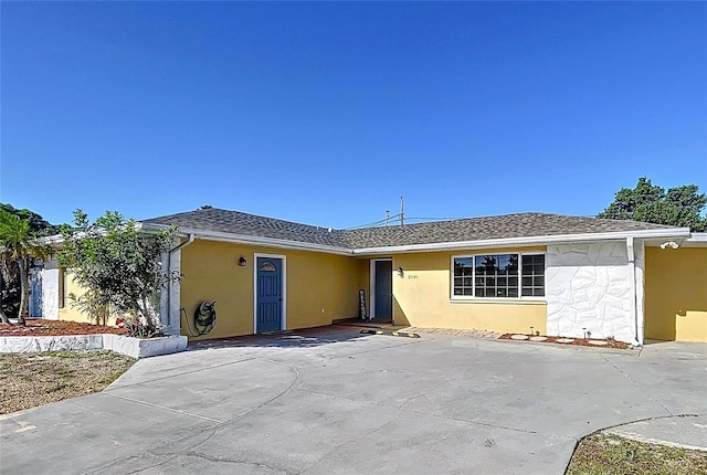 back of property with stucco siding and roof with shingles