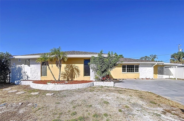 view of front of property with stucco siding, a carport, and fence