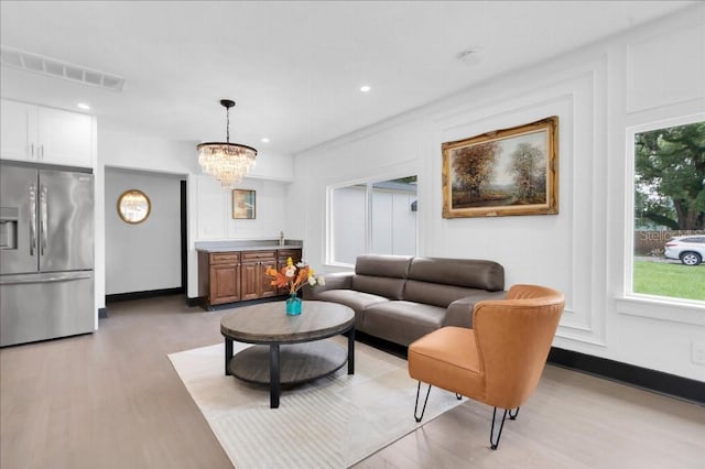 living room with an inviting chandelier and light hardwood / wood-style flooring