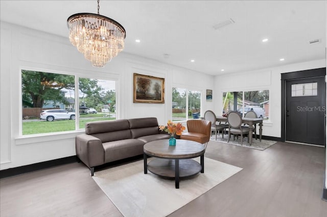 living room featuring wood-type flooring, a notable chandelier, and a wealth of natural light