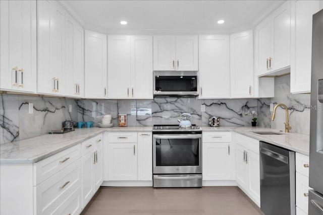 kitchen with appliances with stainless steel finishes, sink, decorative backsplash, and white cabinetry