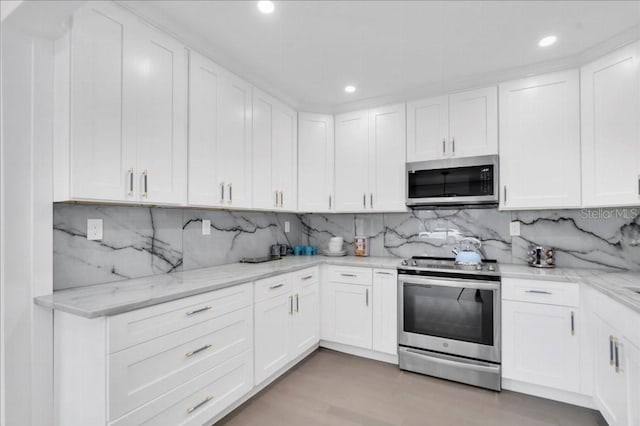 kitchen with stainless steel appliances, light wood-type flooring, decorative backsplash, and white cabinetry