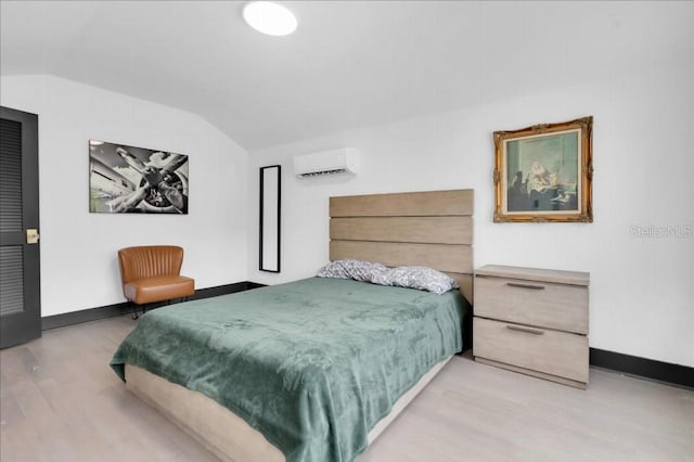 bedroom featuring lofted ceiling, light hardwood / wood-style flooring, and a wall unit AC