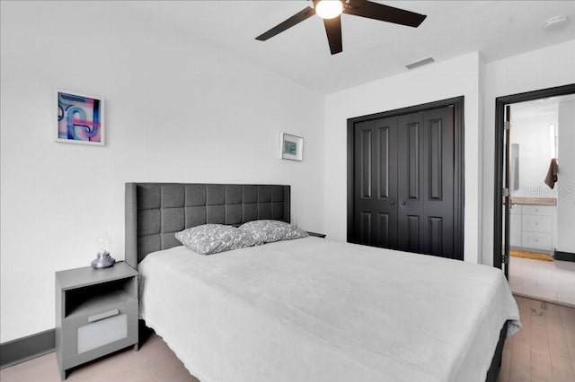 bedroom featuring ceiling fan, ensuite bathroom, a closet, and light hardwood / wood-style floors