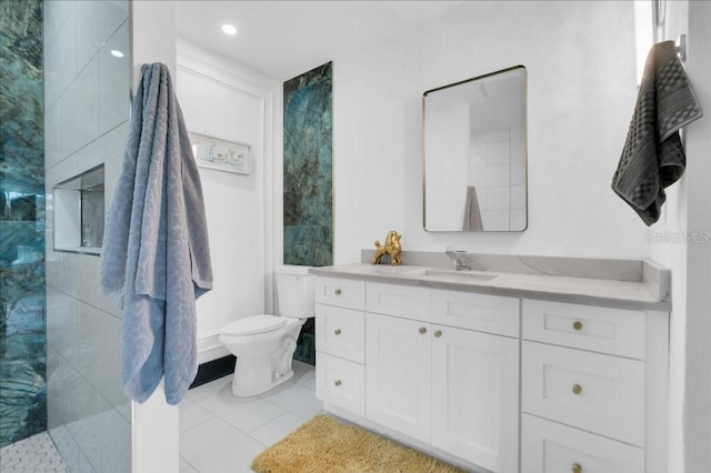 bathroom featuring a tile shower, vanity, toilet, and tile patterned floors