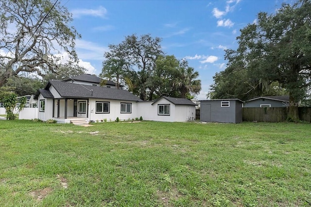 back of house with a lawn and a shed