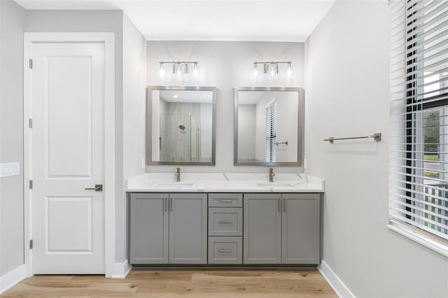 bathroom with a sink, a stall shower, baseboards, and wood finished floors