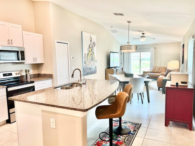 kitchen with a kitchen island with sink, white cabinets, sink, vaulted ceiling, and appliances with stainless steel finishes