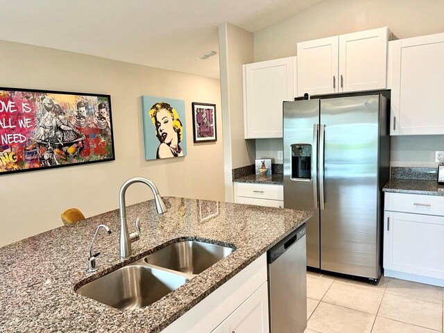 kitchen with appliances with stainless steel finishes, dark stone counters, white cabinetry, and sink