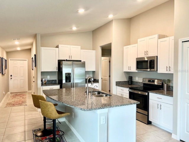 kitchen featuring an island with sink, appliances with stainless steel finishes, sink, and lofted ceiling