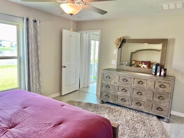 bedroom with multiple windows, ceiling fan, and light hardwood / wood-style floors