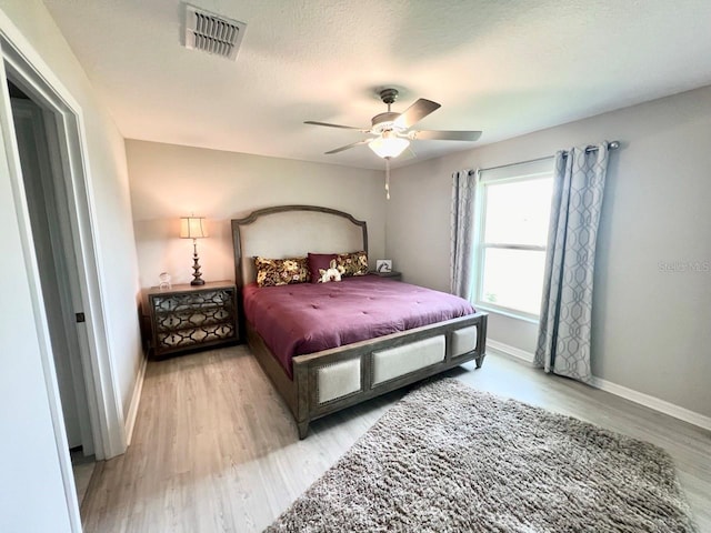 bedroom with a textured ceiling, light wood-type flooring, and ceiling fan