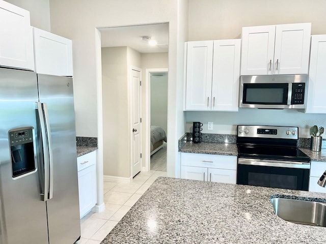 kitchen featuring sink, appliances with stainless steel finishes, light tile patterned floors, and white cabinetry