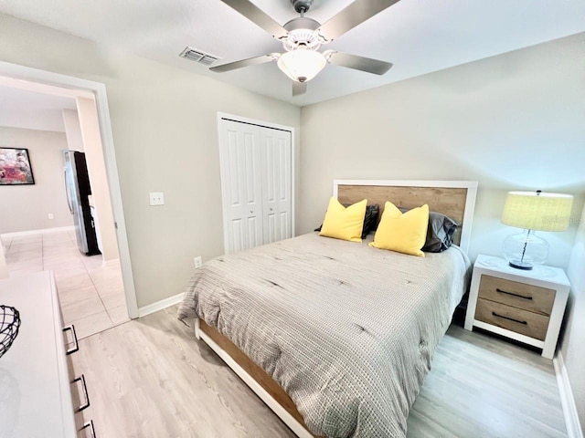 bedroom with hardwood / wood-style floors, ceiling fan, a closet, and stainless steel fridge