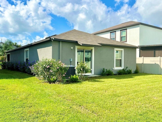 back of property featuring central air condition unit and a lawn