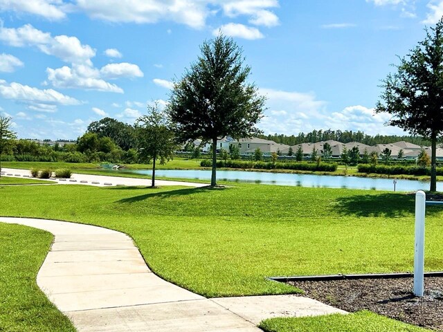 surrounding community with a water view and a lawn