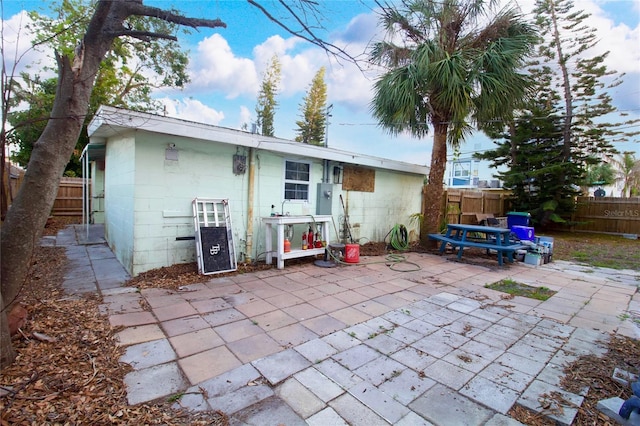 rear view of house with a patio area, a fenced backyard, and concrete block siding