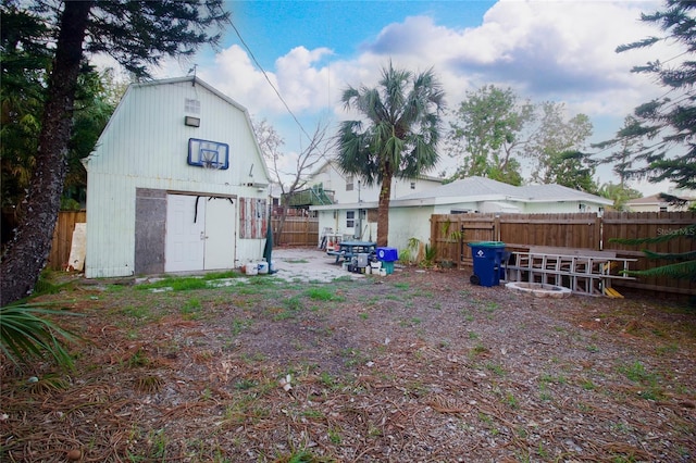 rear view of property featuring a fenced backyard, an outdoor structure, and a storage unit