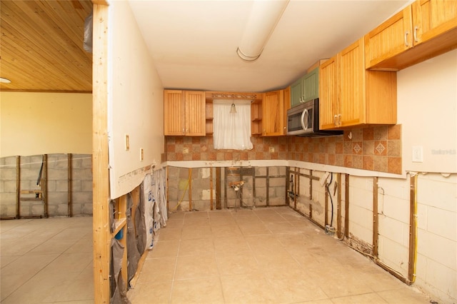 kitchen with light countertops, stainless steel microwave, backsplash, and open shelves