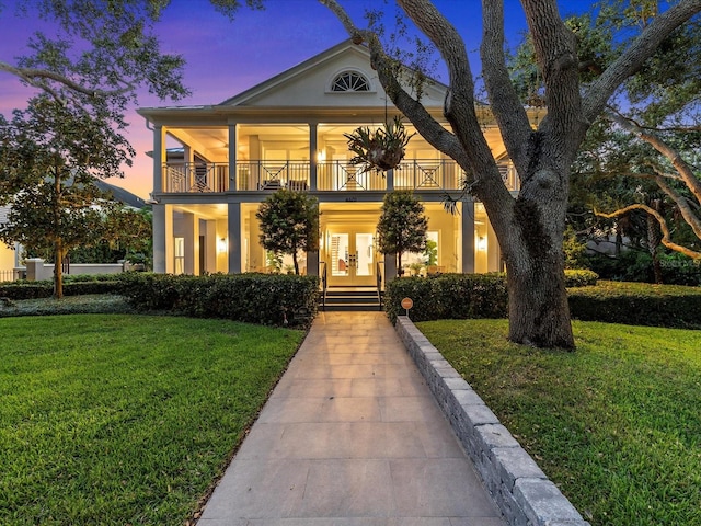 view of front facade with french doors, a balcony, and a yard