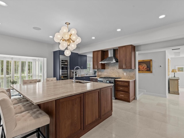 kitchen featuring a kitchen island with sink, tasteful backsplash, sink, wall chimney range hood, and high end stainless steel range