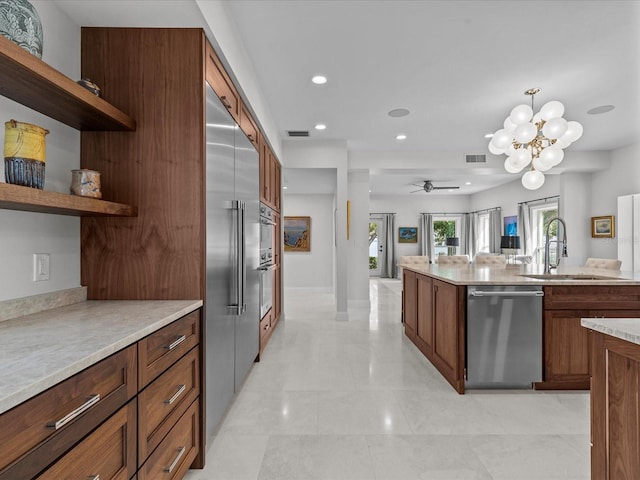 kitchen featuring light stone counters, stainless steel appliances, sink, ceiling fan with notable chandelier, and light tile patterned floors