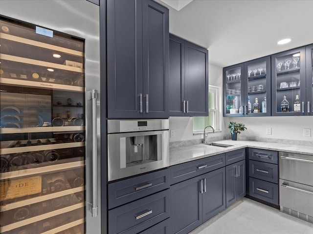 kitchen featuring stainless steel oven, blue cabinetry, wine cooler, and sink