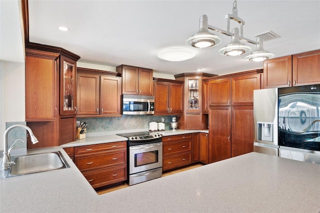 kitchen featuring stainless steel appliances, hanging light fixtures, sink, and tasteful backsplash