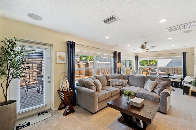 living room with ceiling fan, light colored carpet, a healthy amount of sunlight, and a textured ceiling