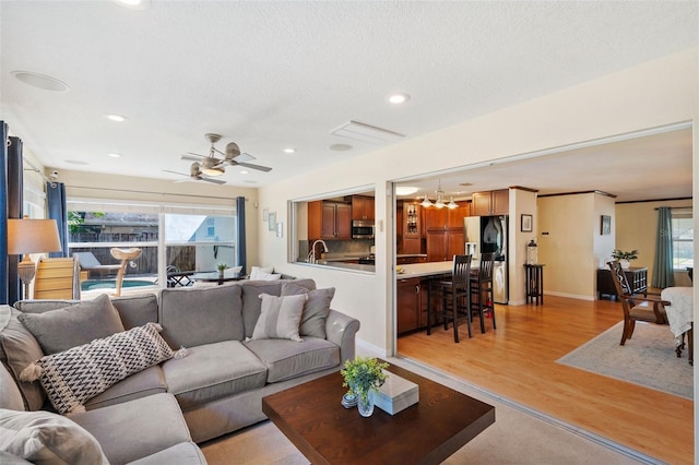 living room featuring ceiling fan, light hardwood / wood-style flooring, sink, and a wealth of natural light