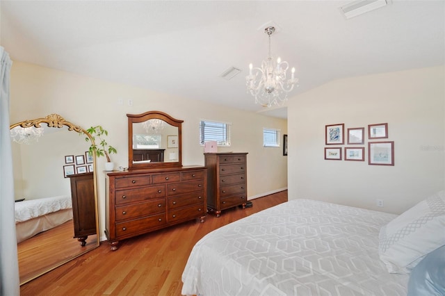 bedroom with an inviting chandelier, wood-type flooring, and lofted ceiling