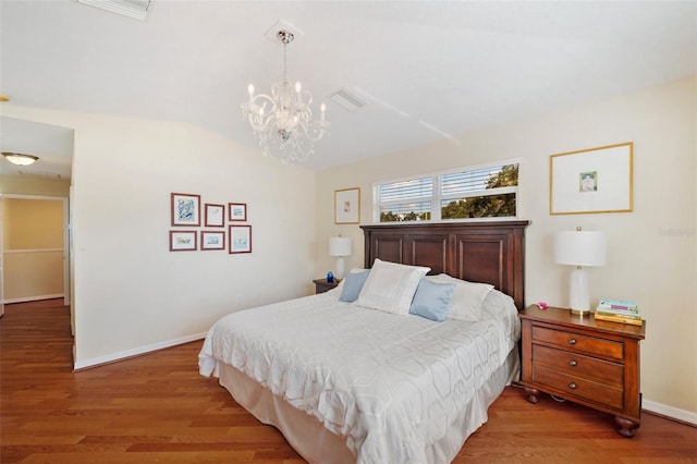 bedroom with an inviting chandelier, lofted ceiling, and hardwood / wood-style floors