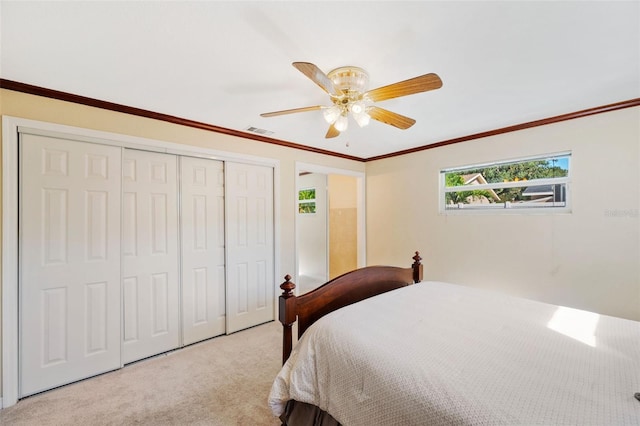 bedroom featuring light carpet, a closet, ceiling fan, and crown molding