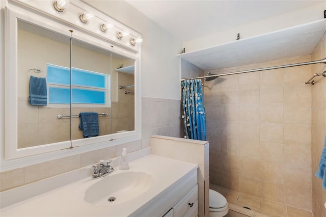 bathroom with walk in shower, tile walls, vanity, and toilet